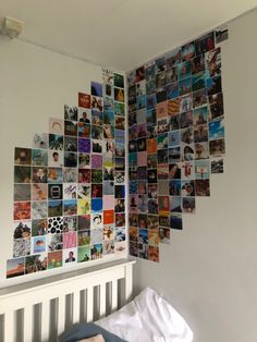 a bed sitting under a white wall covered in lots of different types of pictures on it