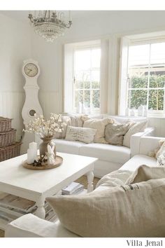 a living room filled with white furniture and lots of pillows on top of couches