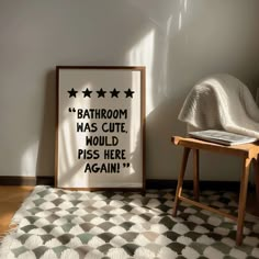 a bathroom has a black and white poster on the wall next to a chair with a blanket