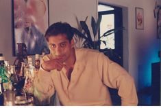 a man sitting at a bar with bottles behind him