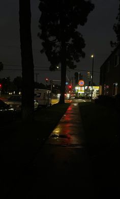 a street at night with cars parked on the side