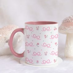 a pink and white coffee mug sitting on top of a table next to two mushrooms