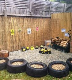 there are many tires on the ground in front of a wall with logs and other items