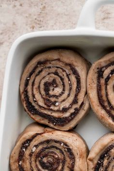 four cinnamon rolls in a white baking dish