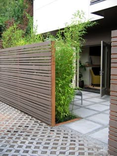 an outdoor area with a wooden fence and green plants on the side of the building