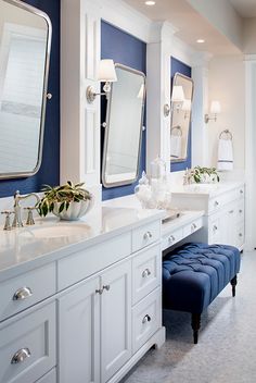 a large bathroom with two sinks and blue accented walls, along with white cabinetry