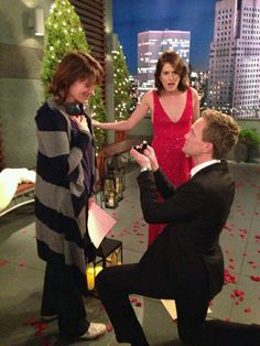 a man kneeling down in front of a woman on the set of a tv show