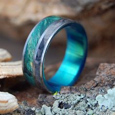 a blue ring sitting on top of a rock next to some sea shells and starfish