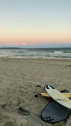 two surfboards are laying on the sand at the beach