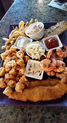 a blue plate topped with fried food and dipping sauces on top of each other