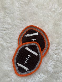 two crocheted footballs sitting on top of a white rug