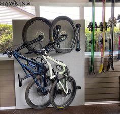 two bikes are hanging on the wall with skis and snowboards attached to it