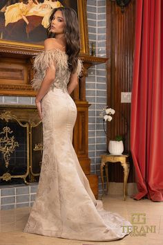 a woman is standing in front of a fireplace wearing a dress with feathers on it