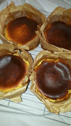 four pastries in brown paper sitting on top of a cooling rack with wax paper