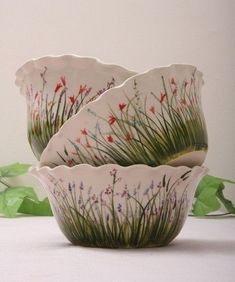 three bowls with flowers and grass painted on them