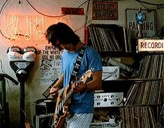 a man playing an electric guitar in a room full of records