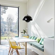 a white table and some yellow chairs in a room with large sliding glass doors to the outside