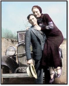 two people standing next to each other in front of an old car