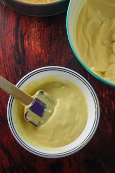 two bowls filled with yellow batter and a wooden spoon in the bowl next to them