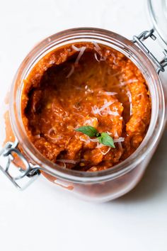 a glass jar filled with food sitting on top of a white table next to a spoon