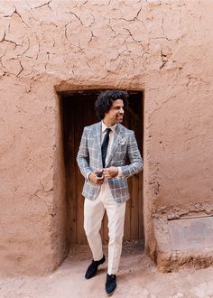 a man in a suit and tie standing next to a building with a door open