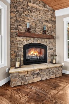 a stone fireplace in a living room with wood floors