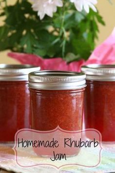 three jars of homemade rhubarb jam on a table with flowers in the background