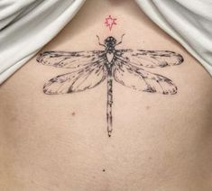 the back of a woman's stomach with a dragonfly tattoo on her chest