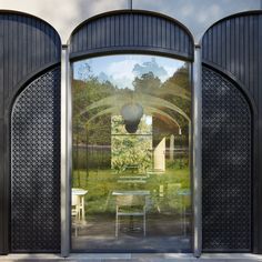 an open door with tables and chairs in front of the entrance to a garden area