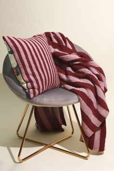 a red and white striped blanket sitting on top of a chair next to a pillow