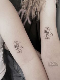 two people with matching tattoos on their arms, one holding the other's arm