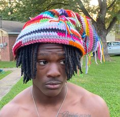 a young man with dreadlocks on his head wearing a multicolored hat