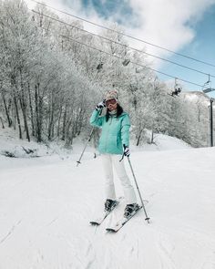 a woman on skis in the snow with trees behind her and wires above her