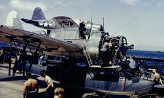 people are standing around an old airplane on the dock