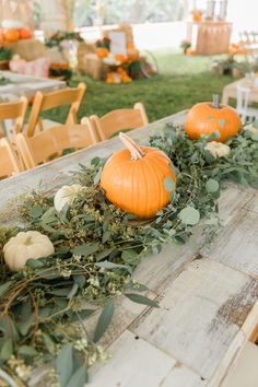 pumpkins and greenery are arranged on the table for an outdoor wedding reception at a farm