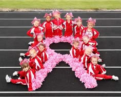 a group of children in red and pink outfits posing for a photo on a track