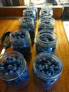 several mason jars filled with blueberries sit on a table