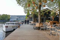 a boat is docked at the end of a pier with tables and chairs on it