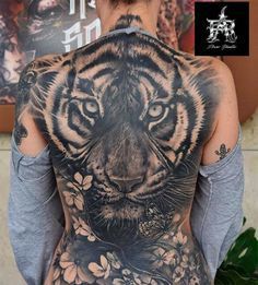 the back of a man with a tiger tattoo on his shoulder and chest, in front of