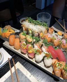 an assortment of sushi on a platter with chopsticks