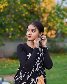 a woman is standing in the grass talking on her cell phone while wearing a black and white dress