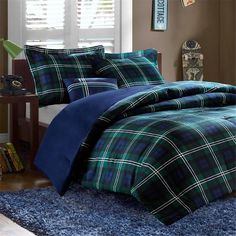 a blue and green plaid comforter set on a bed in a room with windows