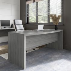 an office desk with two laptops and a phone on it in front of a window