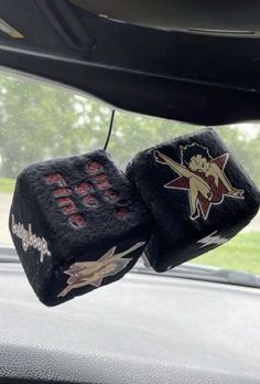 two black dices with red and white designs on them hanging from the dashboard of a car