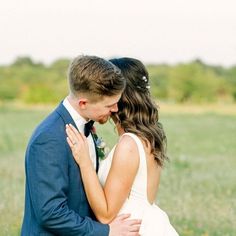 a bride and groom embracing in a field