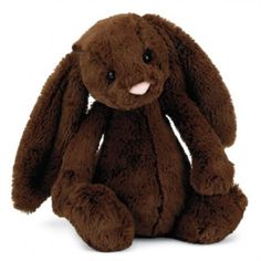 a brown stuffed rabbit sitting up against a white background