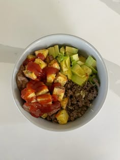 a bowl filled with meat and vegetables on top of a white countertop next to a fork