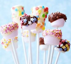 cake pops with sprinkles and toppings on sticks in front of blue background