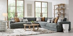 a living room filled with lots of furniture next to two large windows and a rug on the floor