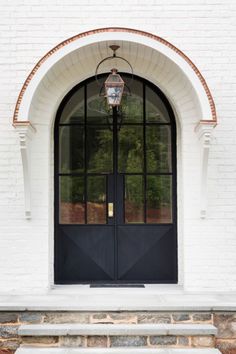 the front door to a white brick building with black doors and steps leading up to it